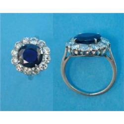 A platinum, sapphire and diamond set cluster ring, the sapphire bordered by a row of 12 brilliant...
