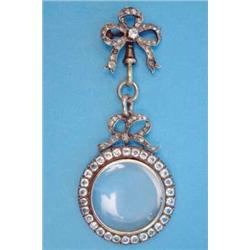 A late 19th century gold circular locket, the frame set clear pastes on a diamond set tied ribbon...