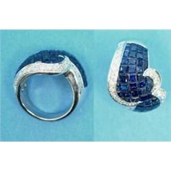 An 18ct white gold dress ring, the shaped wide band invisibly set with sapphires edged by round a...