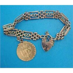 A 15ct gold fancy gatelink bracelet, with padlock clasp and supporting a spade guinea, gross weig...