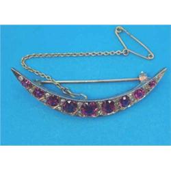 A late Victorian gold crescent brooch, set 9 graduated round cut rubies spaced by pairs of small...