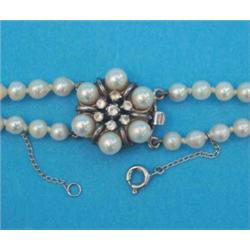 A 2-row graduated cultured pearl necklace, with silver flowerhead clasp, set cultured pearls and...