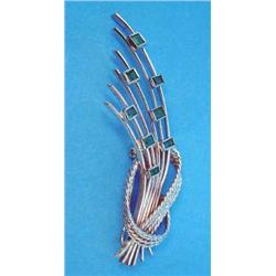 An 18ct white gold stylised tied ribbon floral spray brooch, millegrain set 8 rectangular cut eme...