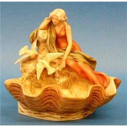 ROYAL DUX PORCELAIN GROUP, Bohemian. 20th Century. Of a young maiden sitting on a rock with two...