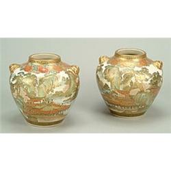 A pair of Japanese Satsuma ovoid vases with lion mask handles, each decorated with figures on a t...