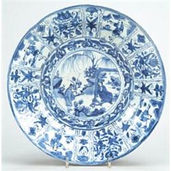 A Chinese Kraaksporselein dish, typically decorated in underglaze blue with a sholar and attendan...