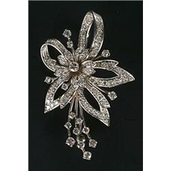 A diamond spray brooch with a central flower-head cluster within a leaf and ribbon loop surround,...