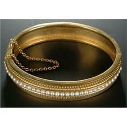 A Victorian gold and half-pearl bangle, the front with a central row of half-pearls between beade...