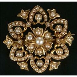 An Edwardian gold and half-pearl brooch centred with a flower-head within an open hexafoil border...