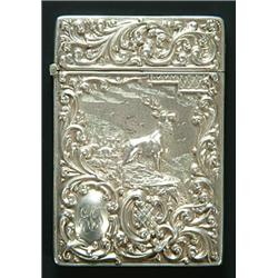 An embossed silver card case the front with a panel depicting a stag and deer in a highland lands...