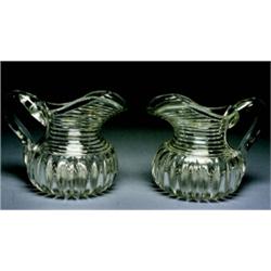 A pair of Georgian Glass Water Jugs, Irish, c.1820, The bulbous loebed bodies and heavy strap ha...