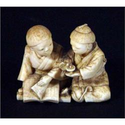 Carved ivory Japanese figure group of two seated children playing with a spinning top, 4cm in len…