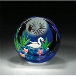 Caithness Glass 1997 "Swan" paperweight, with a white swan floating on blue water with cattails a...