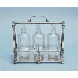 ART DECO - A silver plated tantalus by Christofle. Fitted with three glass decanters and matching…