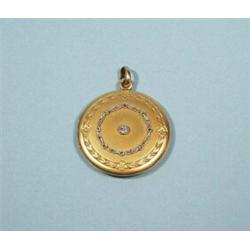 An 18 kt. gold and diamond locket. Top decorated with a central diamond surrounded by a stylized …