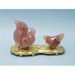 A well carved antique Chinese rosequartz figural group of a rooster and a chicken. On gilt wood n…