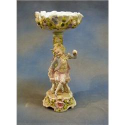A 19th Century Continental porcelain table centre piece in the form of a bonnetted young man sat...