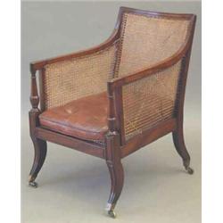 A Regency mahogany bergere chair, with caned back, sides and seat with reeded frame and buttoned...