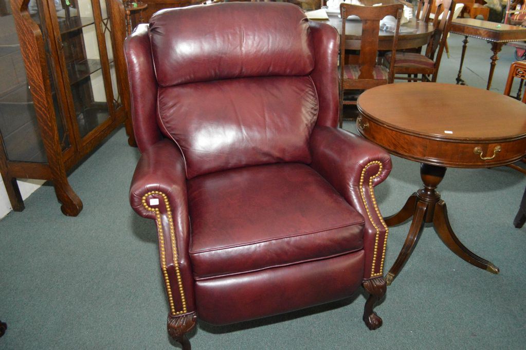 Leather upholstered wing back recliner with carved ball and claw feet, brass nail head decoration