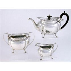 A George V three piece oval teaset, beaded border, melon lobed body, scrolled handle, on four paw...