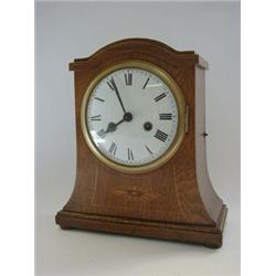 AN EDWARDIAN OAK MANTEL CLOCK, arched outswept oak case, inlaid patera, 15cm enamel Roman dial, h...