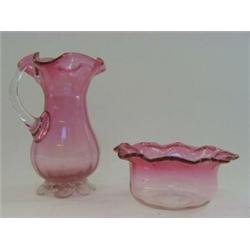 A RUBY GLASS JUG, wavy rim, clear loop handle and pincered foot, height 15cm and a low bowl (2)...