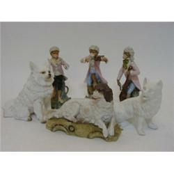 A TINTED BISQUE LYING DOG FIGURE, c.1900, two in plain white and three bisque monkey band figures...