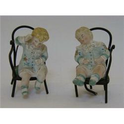 A PAIR OF TINTED BISQUE PIANO BABY FIGURES, late 19th Century, seated on bentwood chairs, height...