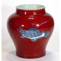 Red glazed oriental vase transfer printed with a band of blue and white fish, 21cm high…