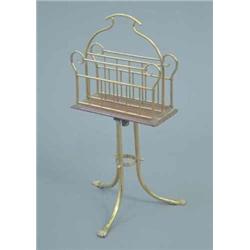 An Edwardian brass and oak revolving canterbury on tripod base with claw feet, height 2ft.4ins....
