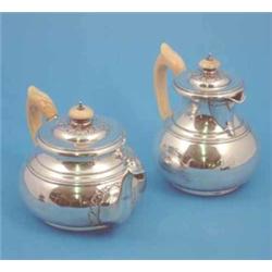 A George V silver teapot and matching hot water pot of compressed circular form with cut card dec...