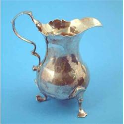 A George III silver baluster cream jug with scroll feet, 1772....