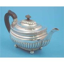 A George III silver teapot of demi fluted rounded rectangular form with ebonised handle and ball...