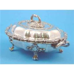 A Victorian plated tureen and stand of serpentine oval form with floral scroll border....