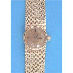 A lady's 18ct gold Omega wrist watch with circular gilt dial and integral textured bracelet....