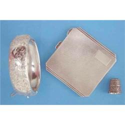 An Art Deco engine turned silver powder compact, a silver thimble and a silver hinged bangle with...