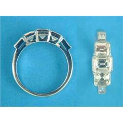 A white gold 3-stone diamond ring, the millegrain set rectangular cut stones flanked by baguette...