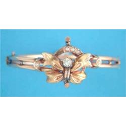 A gold hinged bangle, the tied ribbon front set with a clear paste and seed pearls...