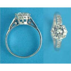 A platinum set solitaire diamond ring, with diamond shoulders, the brilliant cut stone approximat...