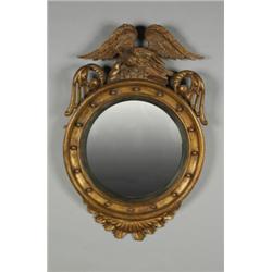 AN EARLY 19TH CENTURY CARVED GILTWOOD FRAMED CONVEX WALL MIRROR, in the Federal manner, surmounte...