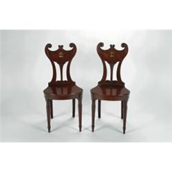 A SET OF FOUR GEORGE II MAHOGANY HALL CHAIRS, the shaped backs centred with an enamelled crest, w...