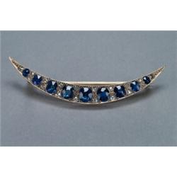 9K YELLOW GOLD AND SILVER CRESCENT BROOCH, set with a double graduated row of 9 oval cut sapphire...