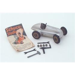 A Schuco tinplate clockwork 1930s Mercedes racing car, no. 1050, including associated spare parts...