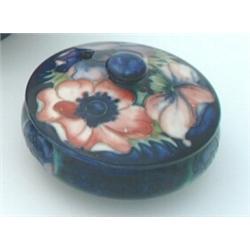 A Moorcroft pot and cover, of circular shape, the blue ground tube-lined with anemones, incised t...