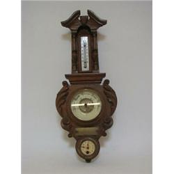 AN EDWARDIAN OAK BAROMETER, elaborate carved case, thermometer over a weather gauge and timepiece...