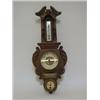 Image 1 : AN EDWARDIAN OAK BAROMETER, elaborate carved case, thermometer over a weather gauge and timepiece...