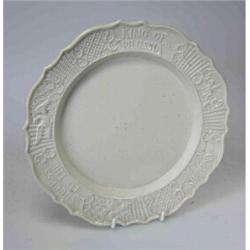 A mid 18th century saltglaze plate, the rim moulded with a cavalryman, an eagle and trophies on bas.