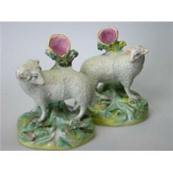 A pair of late 19th century Staffordshire sheep spill vases, the ram and ewe standing over streams..