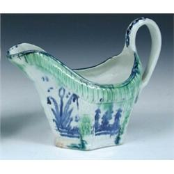 A mid 18th century blue and white creamware jug painted with six foliage panels separated by and be.