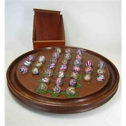 A mahogany solitaire board with Venetian glass marble pieces, the latter with spiral lace and colou.